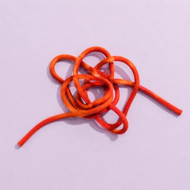 A loose knot of orange cotton cord on lavender paper